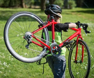 Frog Kids Cyclocross Bike in red being shoulder carried by a child